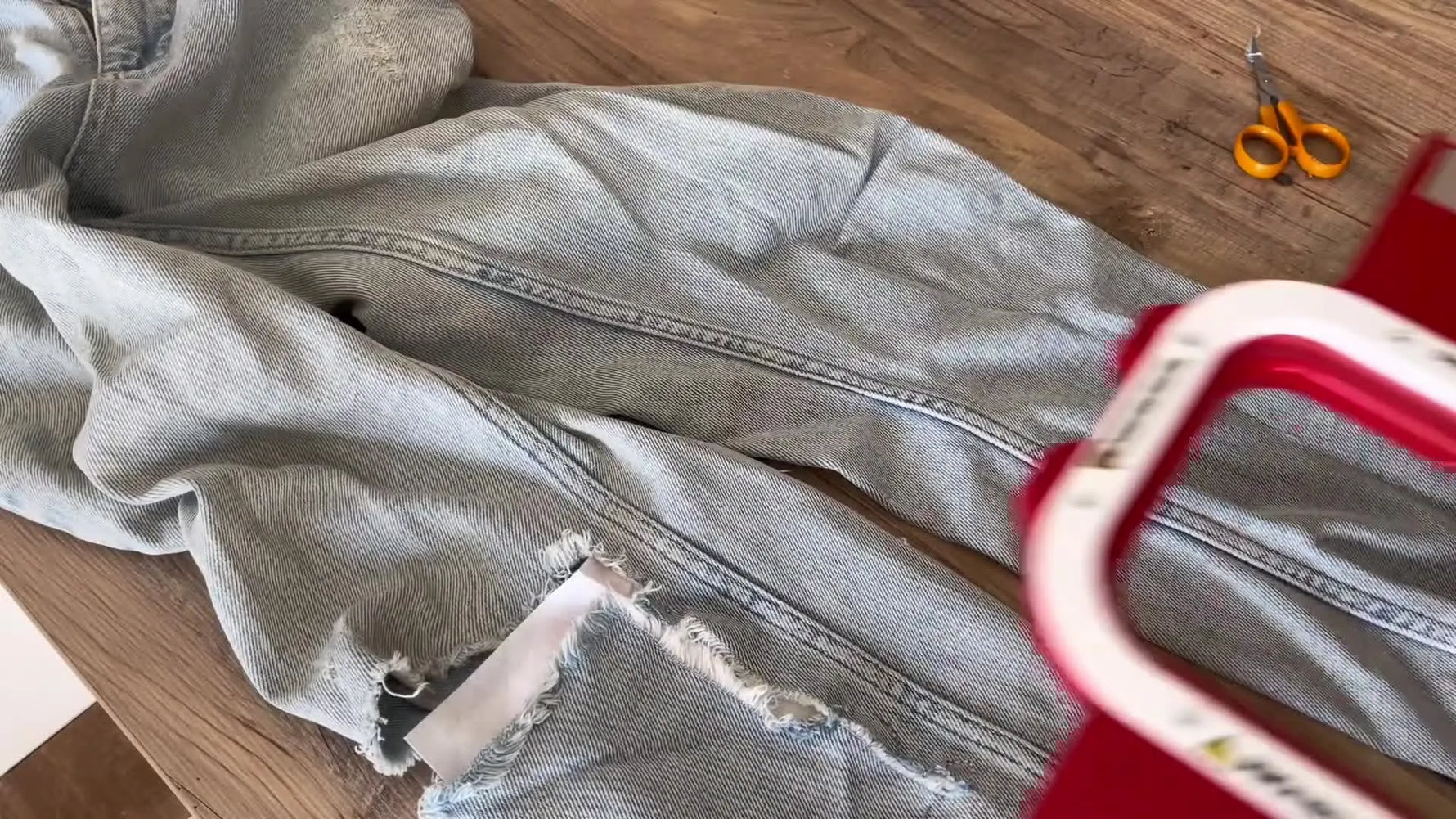 A close-up shows a red magnetic hoop snapping onto a jeans leg, clamping denim and stabilizer securely for embroidery repair.