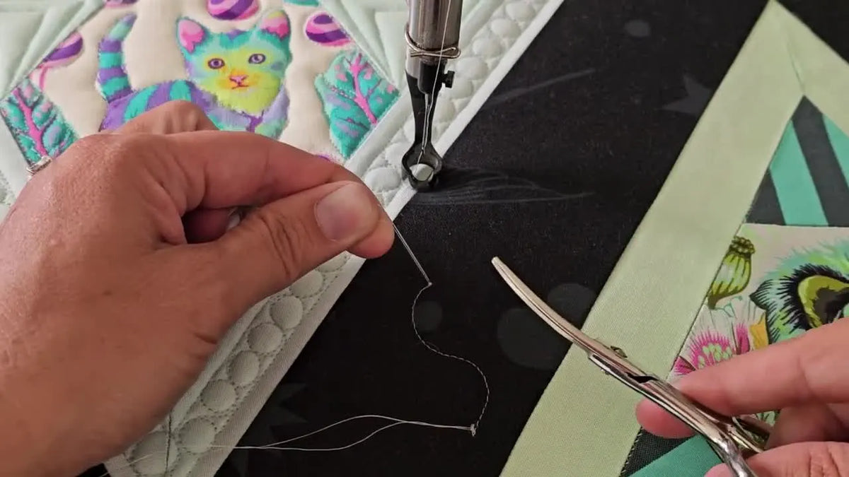 Curved scissors trimming threads near quilt top