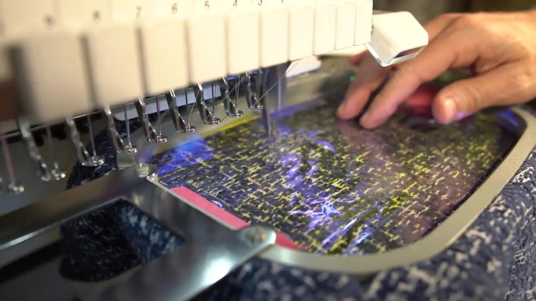 An extreme close-up of the Baby Lock Enterprise stitching a sparkling fill over iridescent Mylar on the mermaid tail.