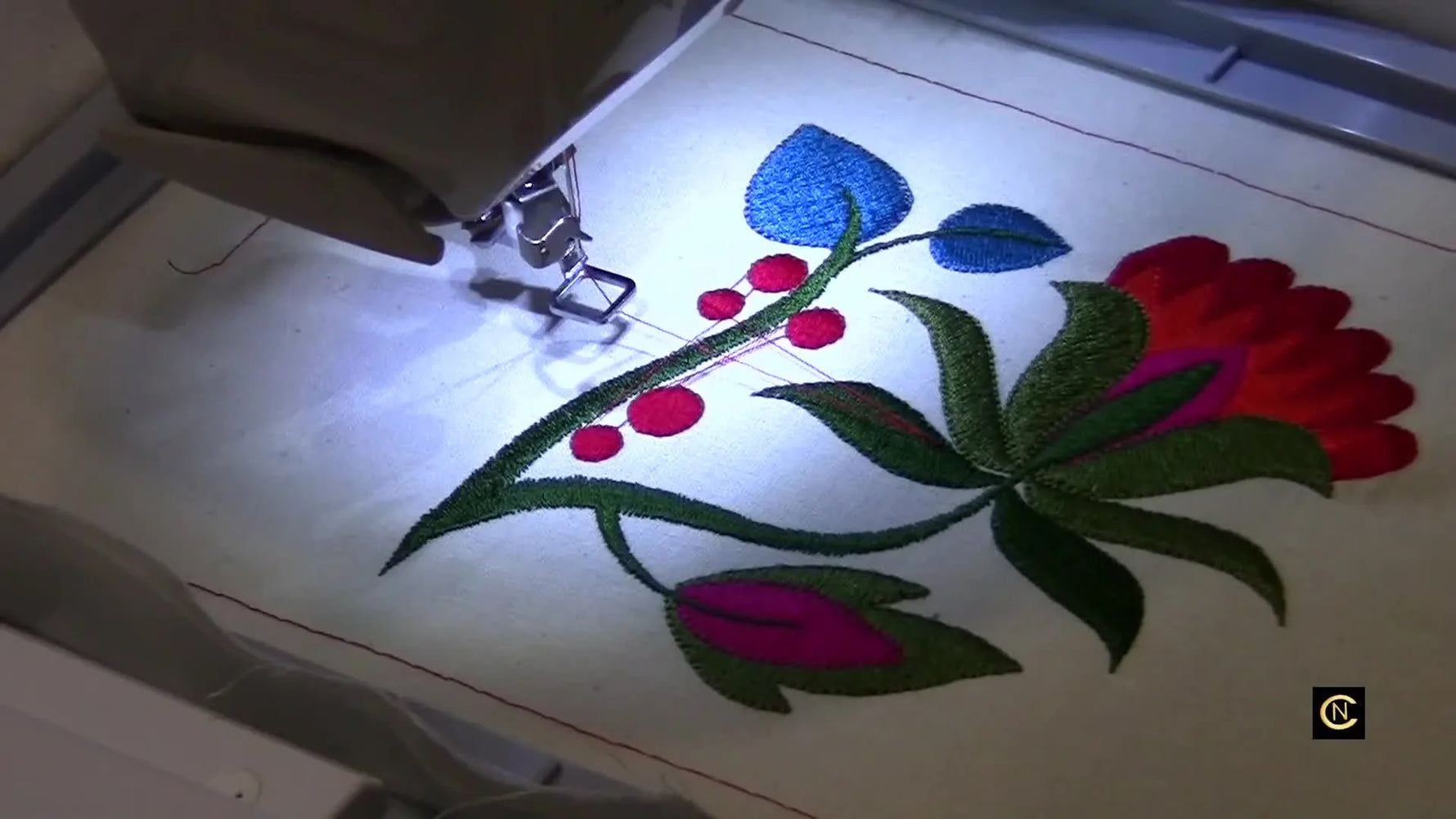 A finished Jacobean floral embroidery sample on thin white muslin showing a flat, pucker-free result after stabilizer and tension adjustments.