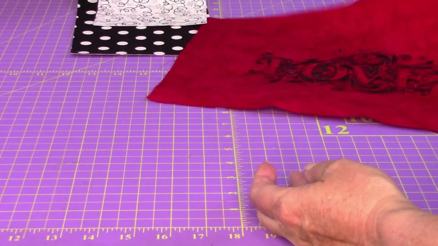 A close-up of the red fabric sample showing the dense “LOVE” embroidery stitched flat with no puckering.