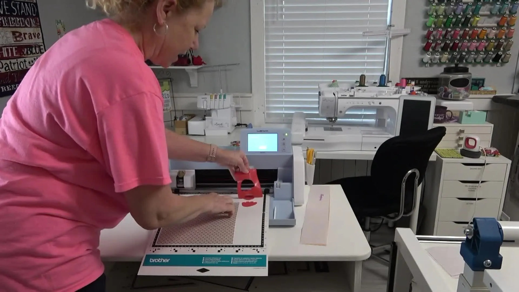 A cleanly cut red appliqué piece is lifted off a ScanNCut low-tack mat with a spatula tool after a precise cut.