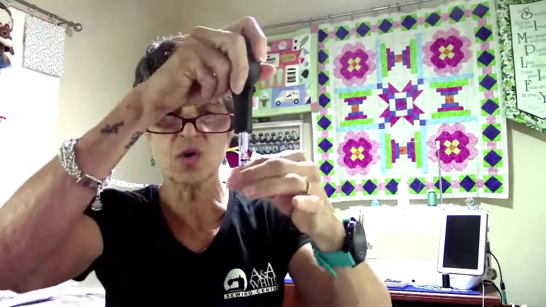 The host holds up the Kimberbell “Cup of Cheer” quilt kit box as a preview of the Advent quilt project.