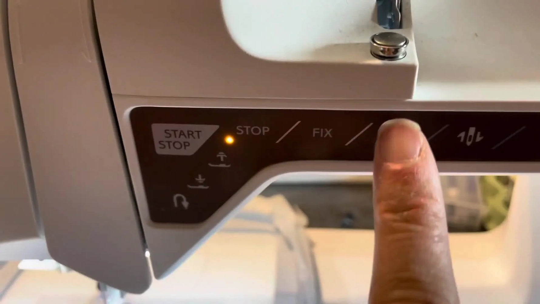 Close-up of a finger pressing the cut button on the Husqvarna Viking Topaz 40 control panel during embroidery.