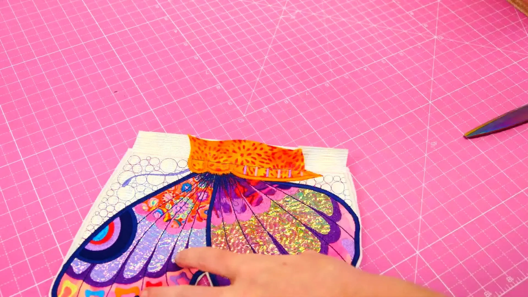 Hands turn the clutch right-side out through the turning opening, revealing the butterfly flap and clean edges.