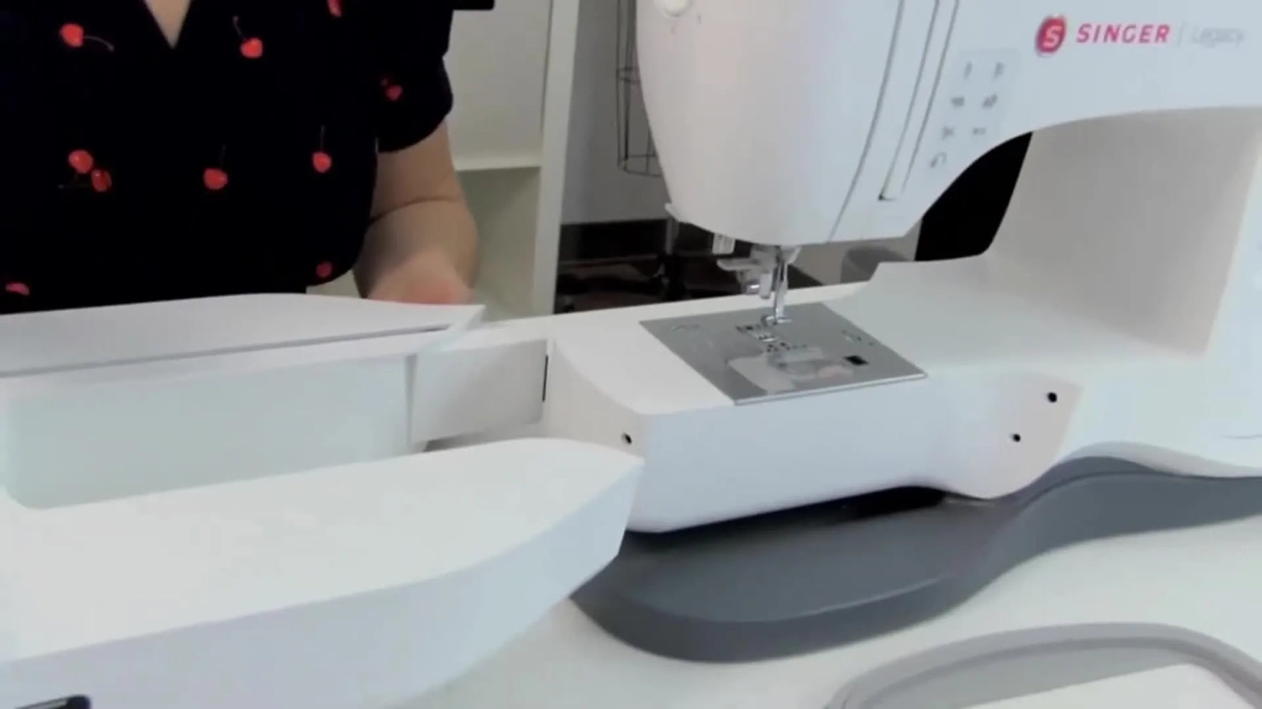 Hands slide the Singer Legacy embroidery unit onto the machine’s free arm until it locks in with a firm snap.