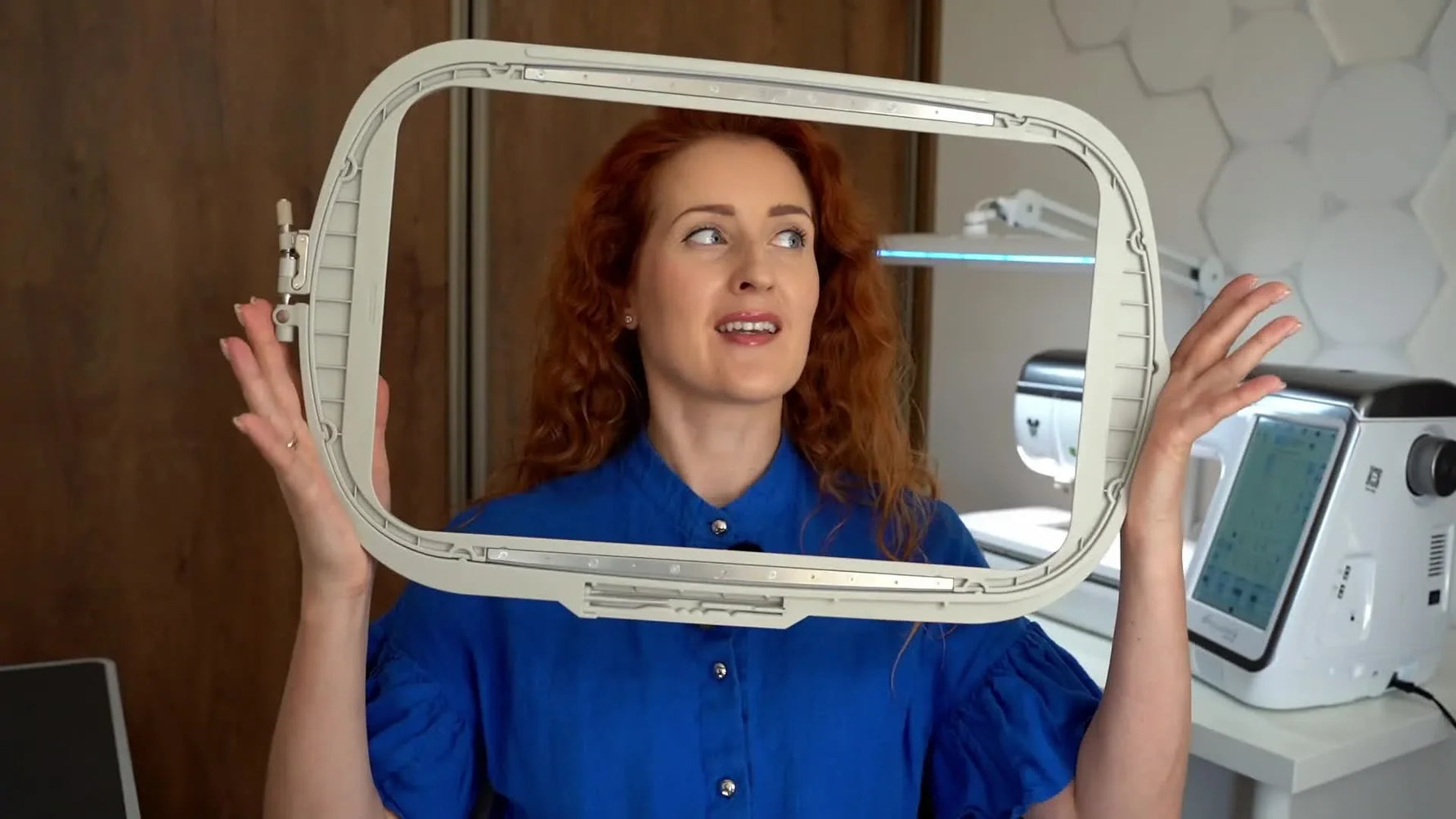 A creator holds an oversized traditional embroidery hoop to show why hooping finished sweaters can be frustrating.