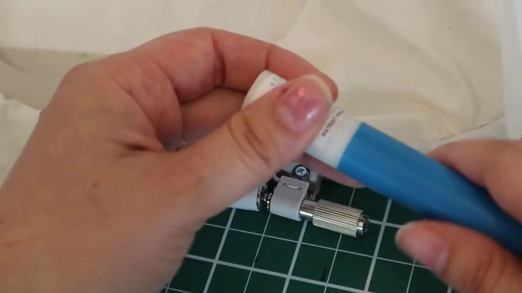 A close-up shows a traditional screw embroidery hoop being tightened with a metal hoop key tool—an exact moment that explains why many embroiderers later upgrade their hooping workflow.