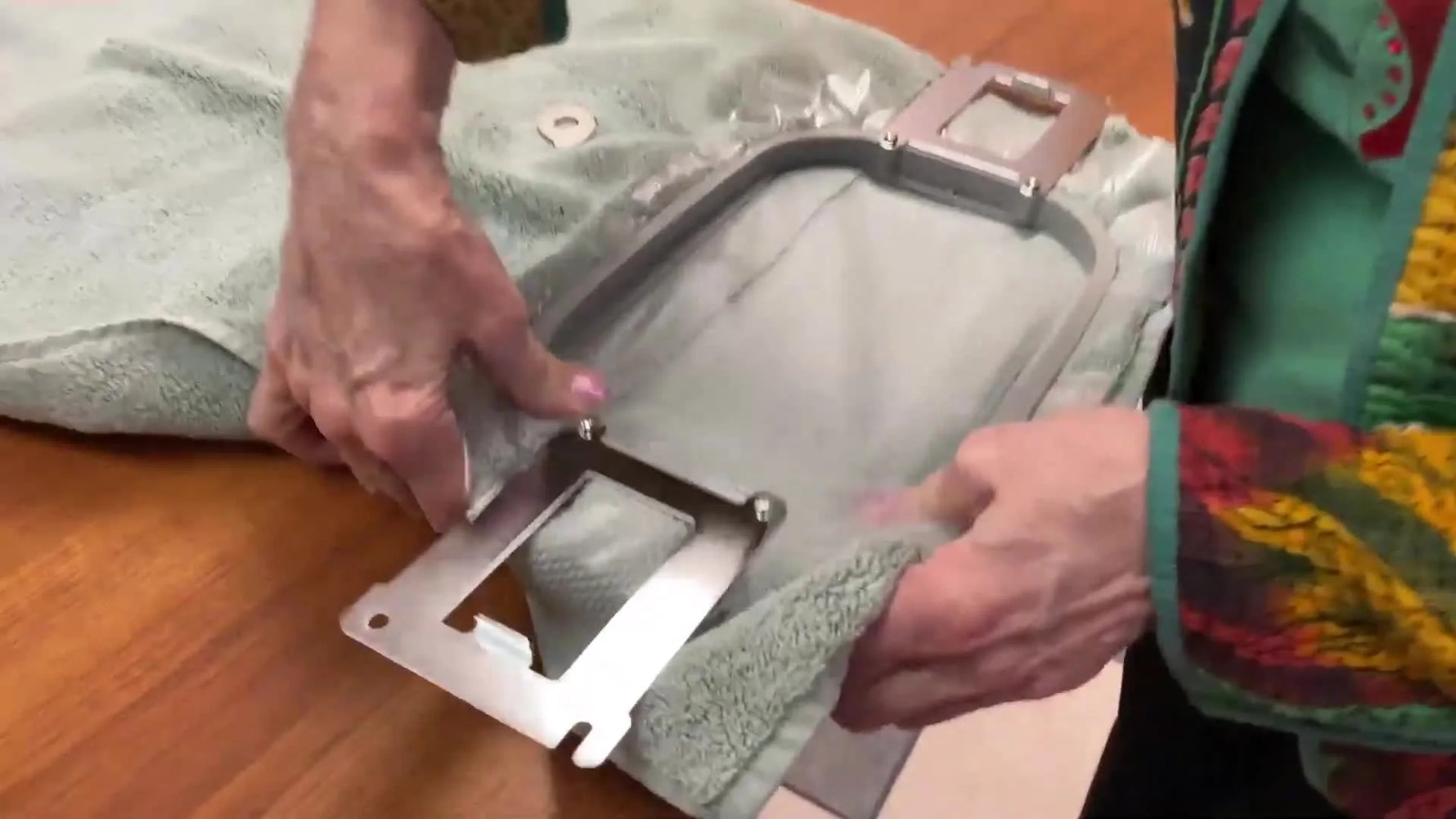 A close-up of a thick terry towel being clamped securely inside a metal magnetic hoop with stabilizer layers above and below.