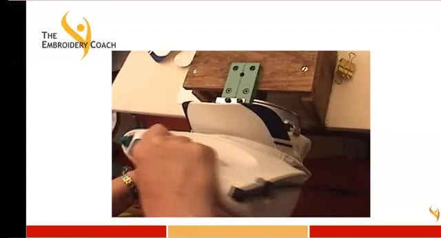 A household steam iron is pressed firmly onto a structured cap front mounted on a cap framing device to soften buckram and flatten the center seam hump.