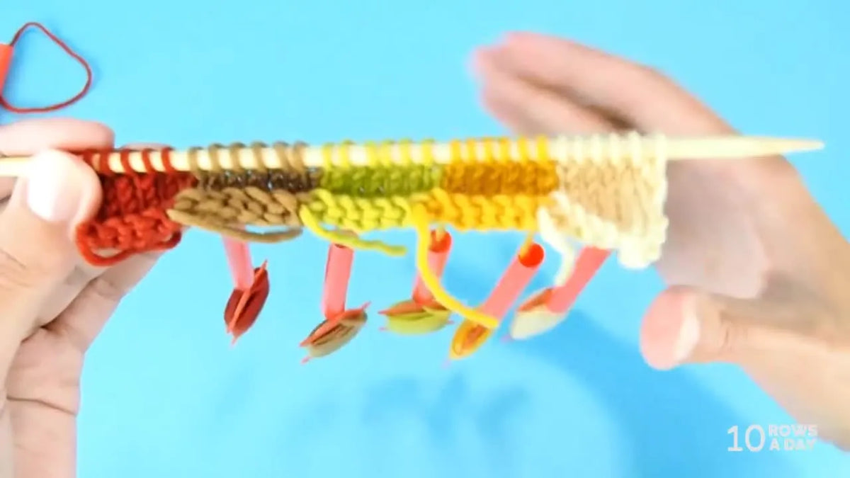 Intarsia knitting project with multiple bobbins and straw spacers in use.