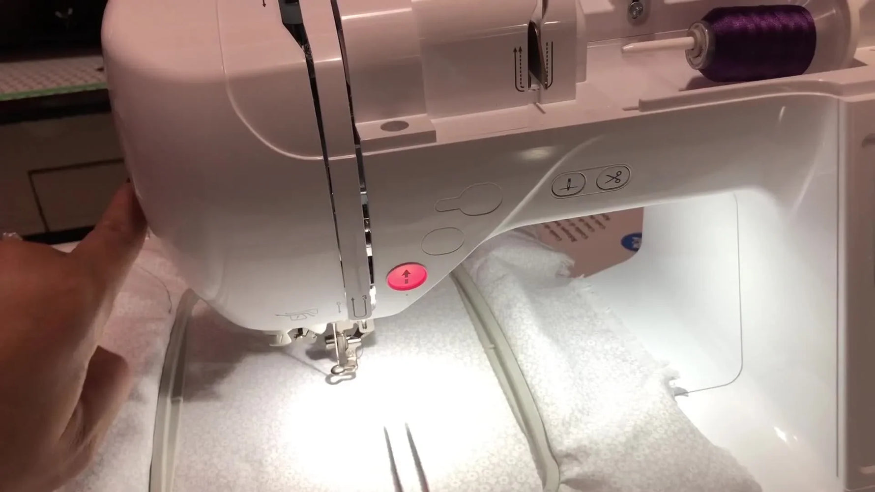 Close-up of the Brother PE800 stitching a purple floral monogram “C” while the presser foot and needle area are in motion.