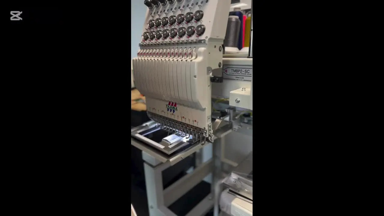 A close-up of a Tajima TMBP2-SC single-head machine showing the 15-needle industrial build and front needle area.
