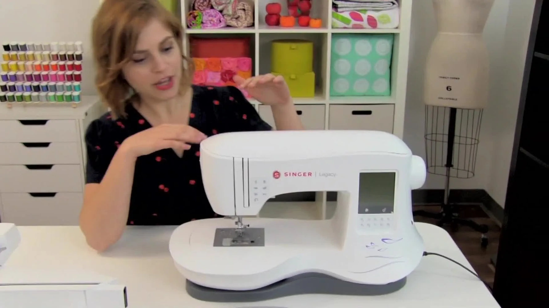 The embroidery unit is being slid onto the Singer Legacy free arm, showing the correct docking position before the final snap-in lock.