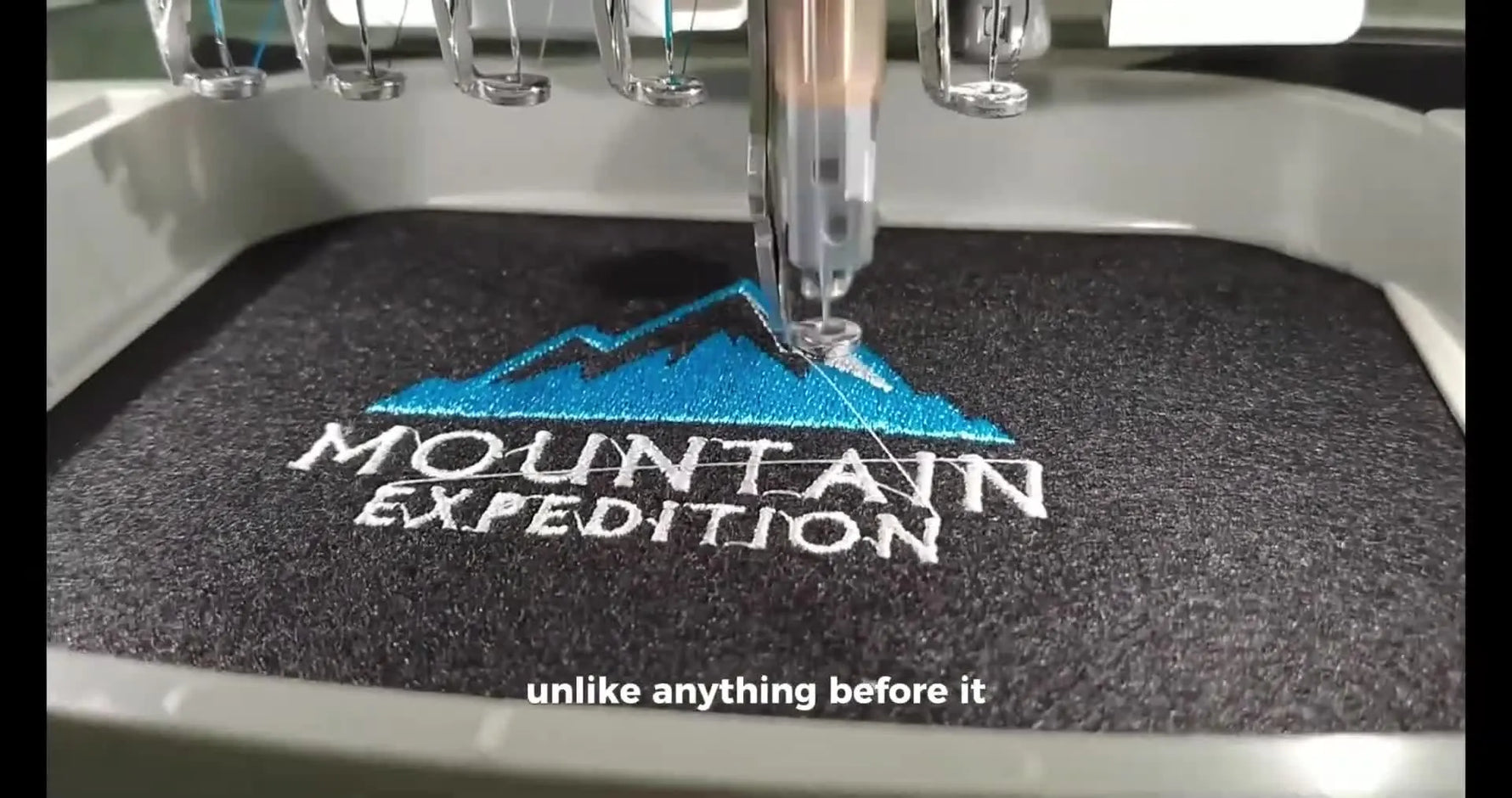A close-up of a machine stitching the “MOUNTAIN EXPEDITION” patch, showing dense fill and clean edge coverage in progress.