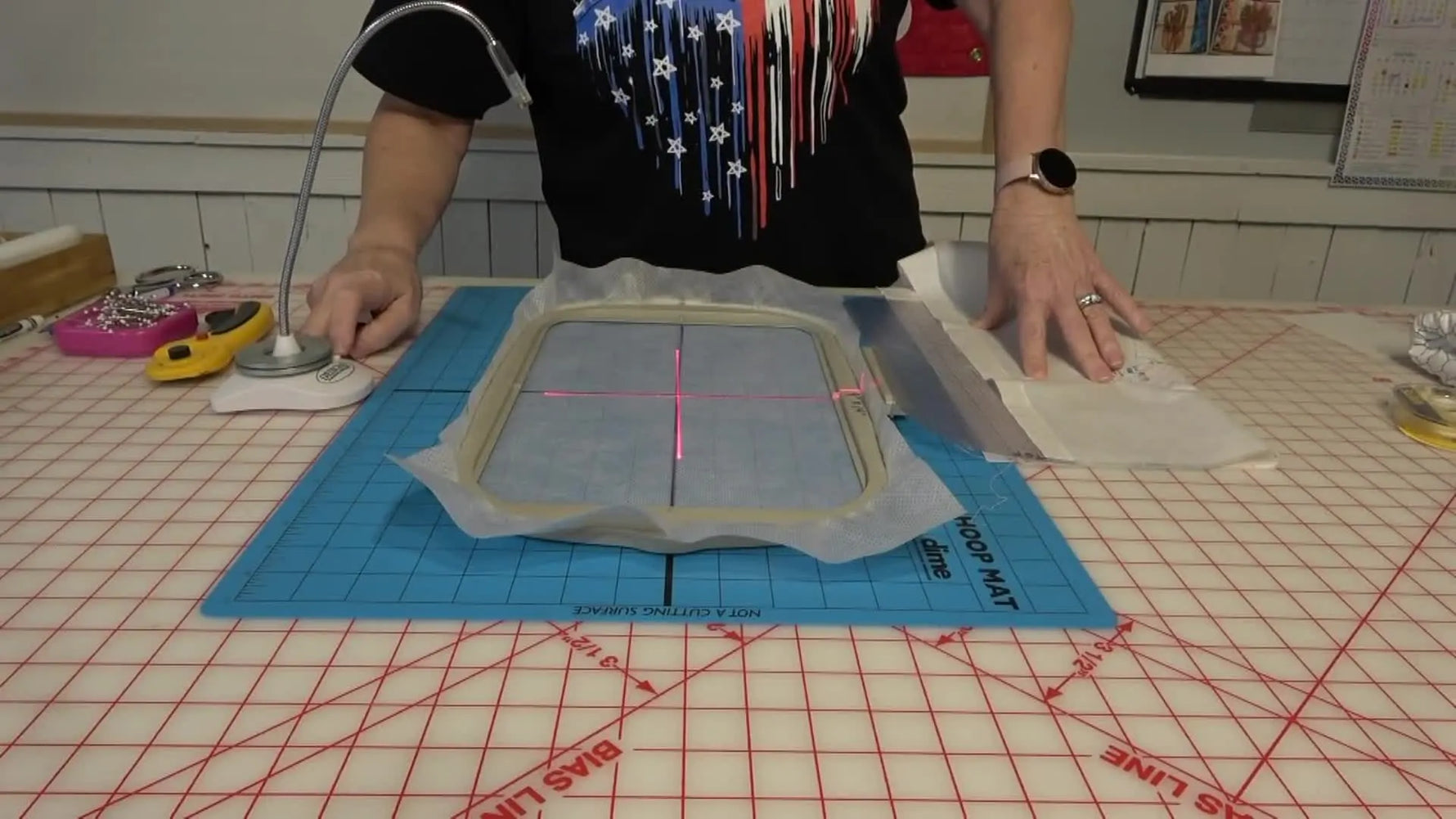 A red crosshair laser shines over a hooped stabilizer and fabric, showing the exact center point needed for perfect multi-hooping alignment.