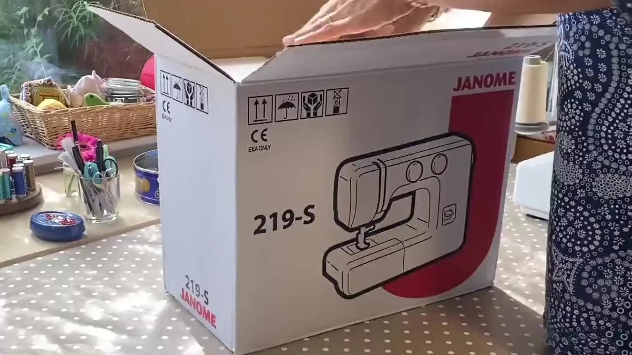 Woman unboxing a Janome 219âS sewing machine from a large cardboard box.