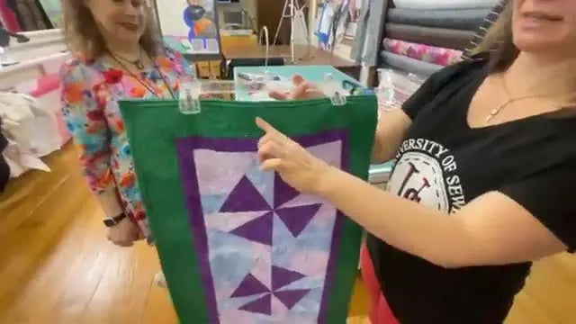 A green and purple quilted table runner showing a seamless embroidery-border connection from a quilting-in-the-hoop technique.