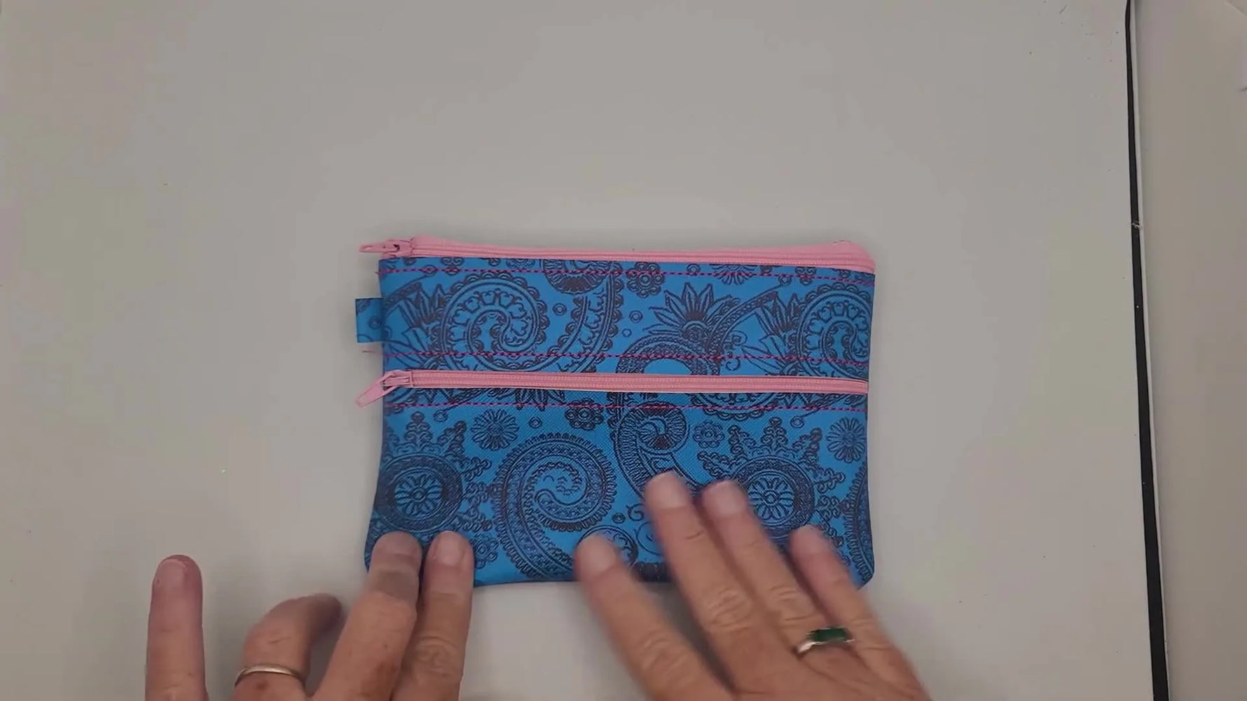 An overhead view of the finished double zipper vinyl bag turned right side out, showing the clean exterior and two zipper openings.