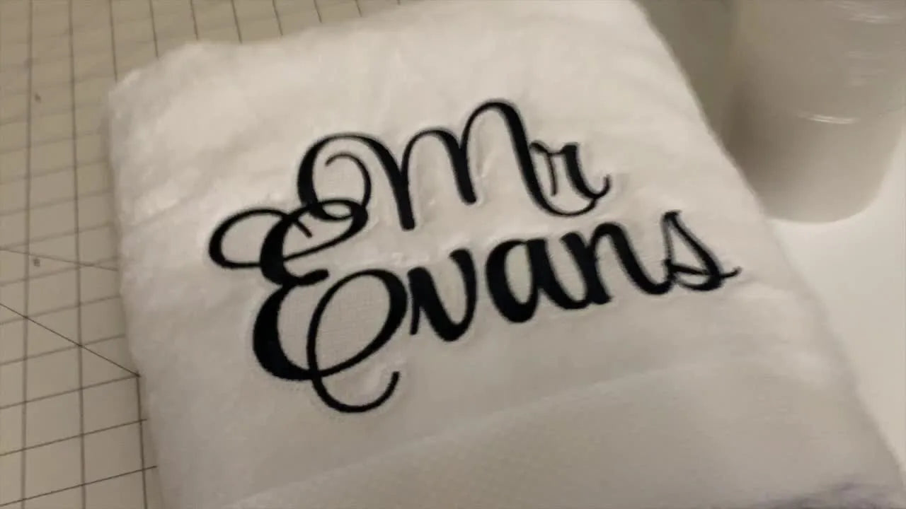 Close-up of a finished towel with crisp black name lettering sitting cleanly on top of plush white terry texture.
