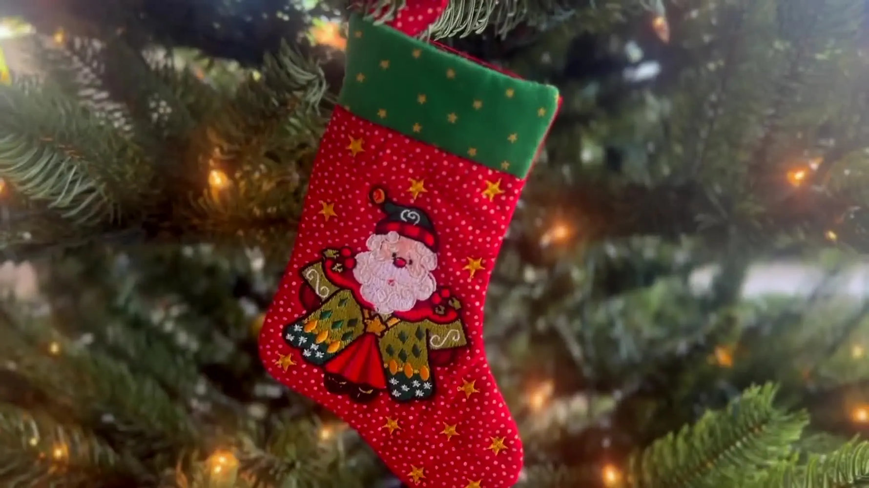 A finished red Santa in-the-hoop stocking hanging on a Christmas tree, showing the clean shape and festive embroidery.
