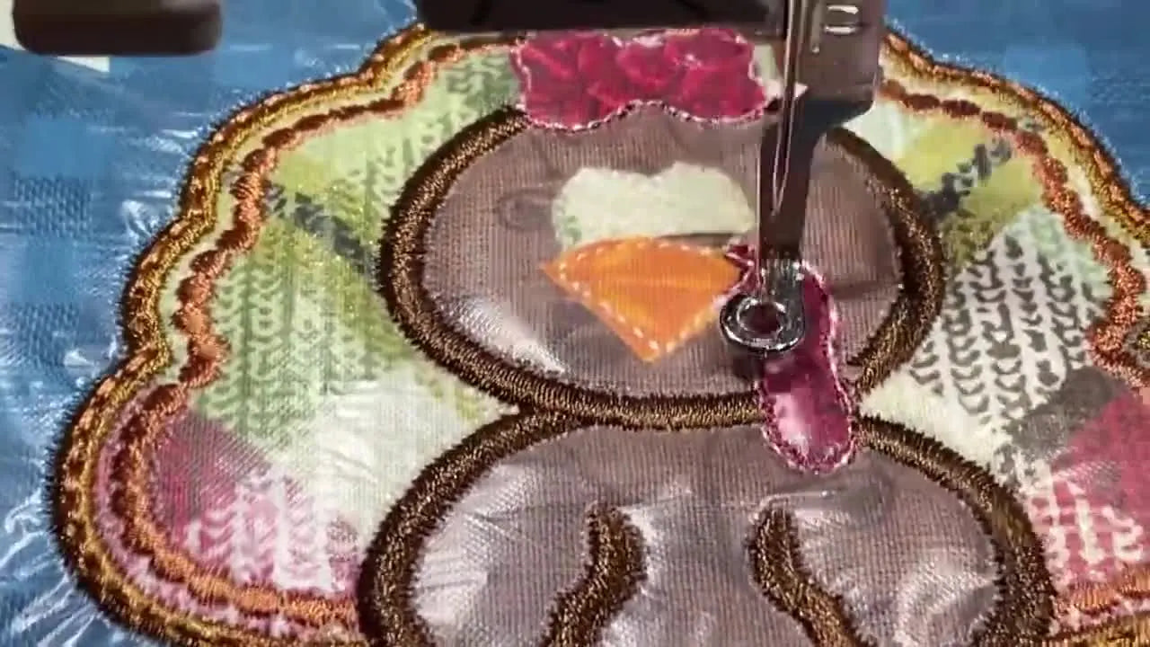 A close-up of the finished turkey appliqué with crisp satin borders and layered fabrics on a blue gingham dress.