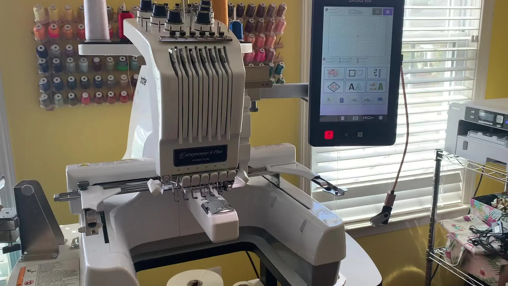 A wide view of the Brother PR670E set up in a craft room, ready for multi-needle threading and production-style embroidery.
