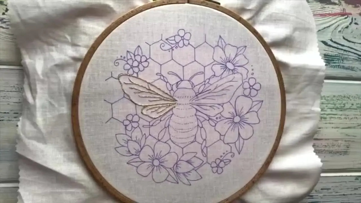 Embroidery hoop with a partially completed bee and floral design