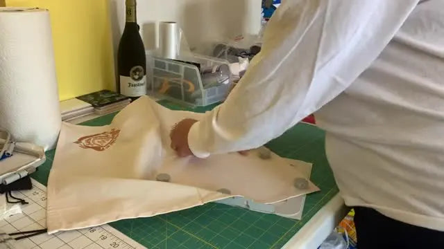 A dinner napkin is floated on sticky stabilizer inside a flat 5x7 magnetic hoop and secured with six cylindrical magnets, ready to slide into a Brother SE1900.