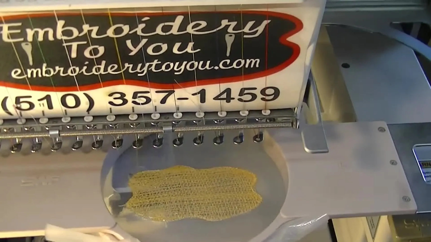A close-up shows the dense yellow fill building a patch background on hooped Madeira E‑Zee Badge Film mid-stitch.