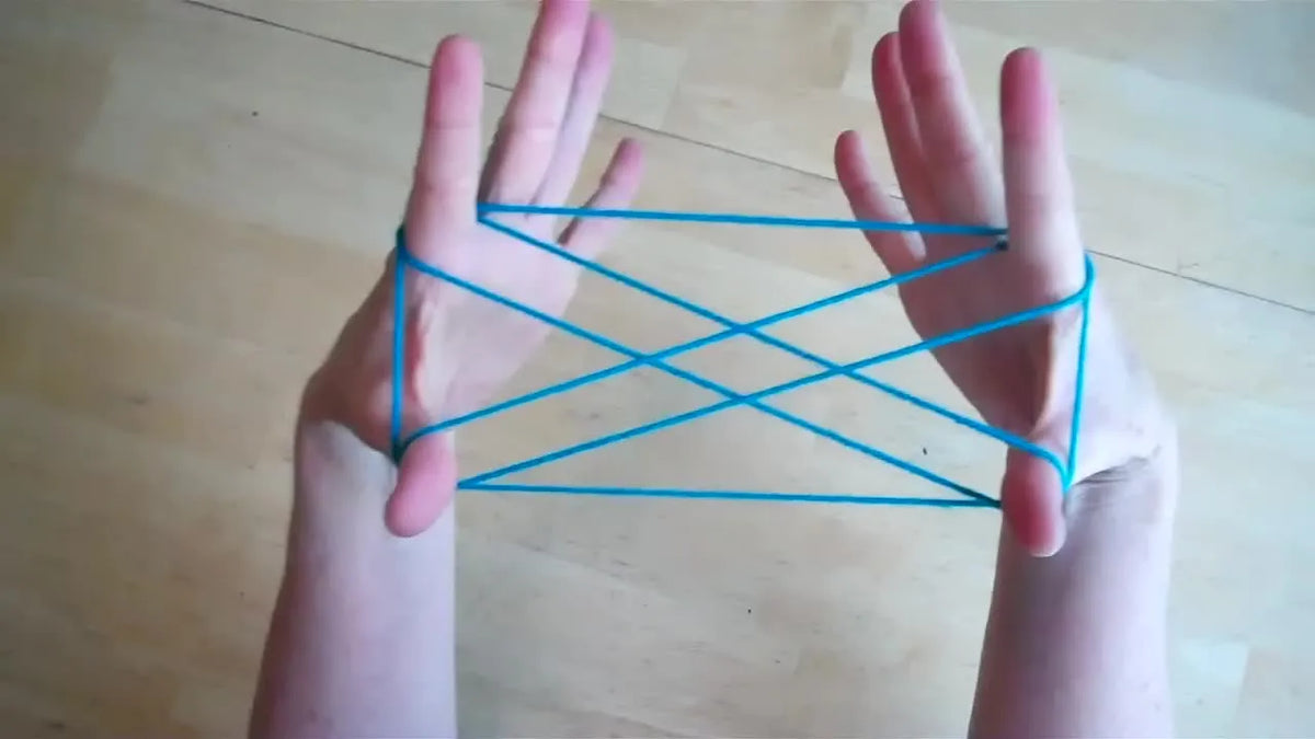 Hands holding a blue string loop in the Cat's Cradle X shape.