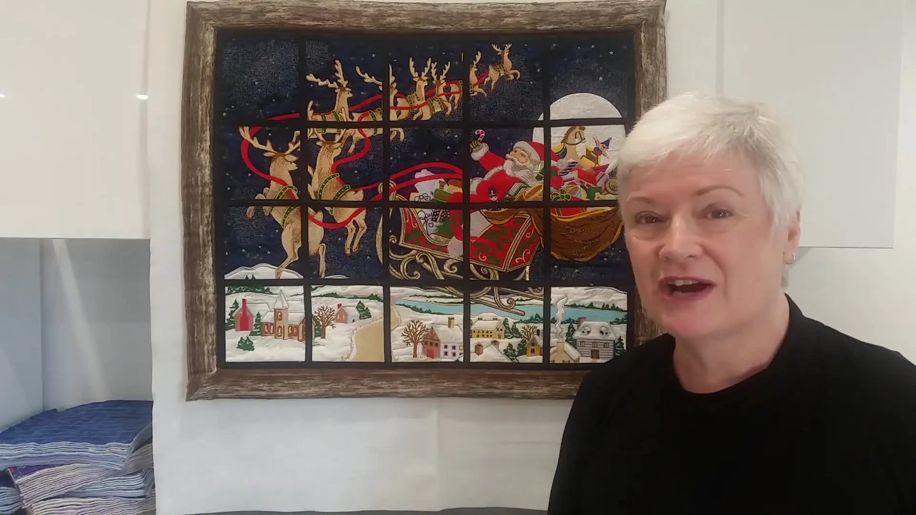 A wide view of the completed, framed Santa’s Ride tiled embroidery finished with black window-pane sashing and a timber-look border.