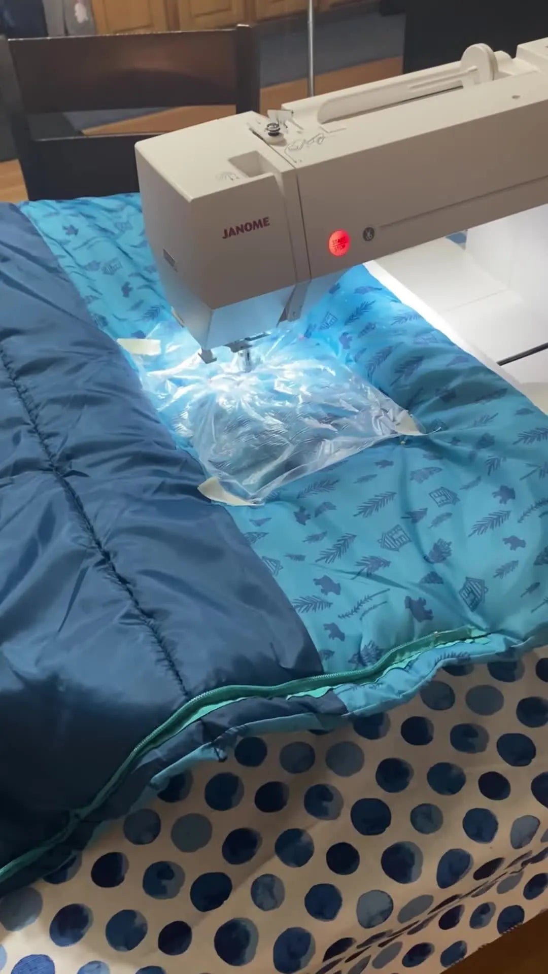 A Janome 550E stitches the name on a bulky nylon sleeping bag while the bag is fully supported on the extension table.
