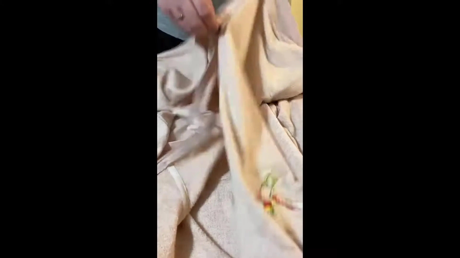 The finished hummingbird embroidery is shown on the upper chest of a light peach zip-up sweater during the final reveal.