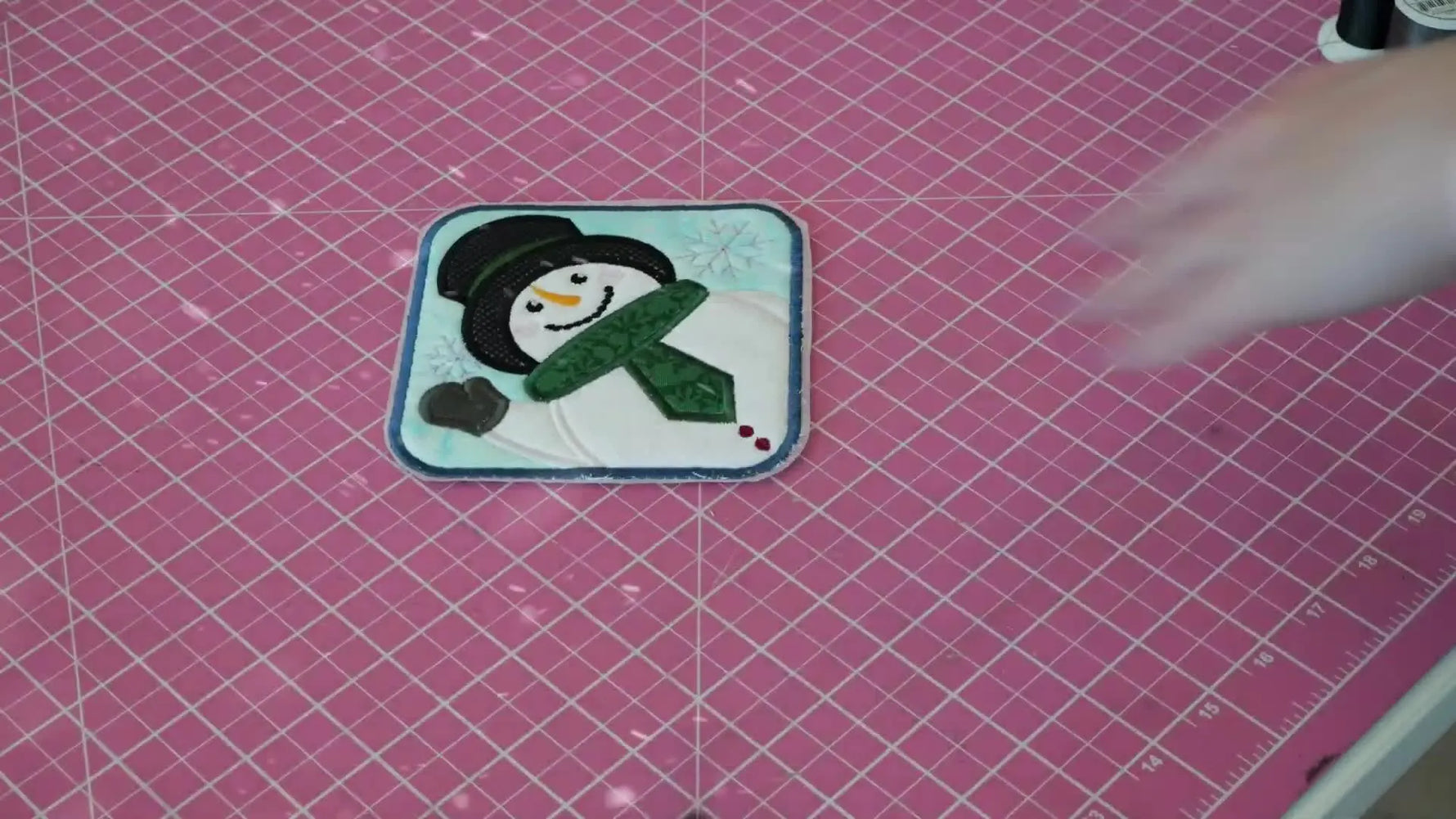 A set of finished snowman coasters laid out together, showing crisp satin borders and clean appliqué edges.
