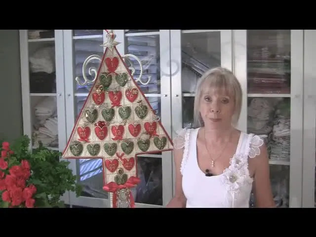 A finished Christmas tree advent calendar with red and green heart pockets arranged across the quilted tree.