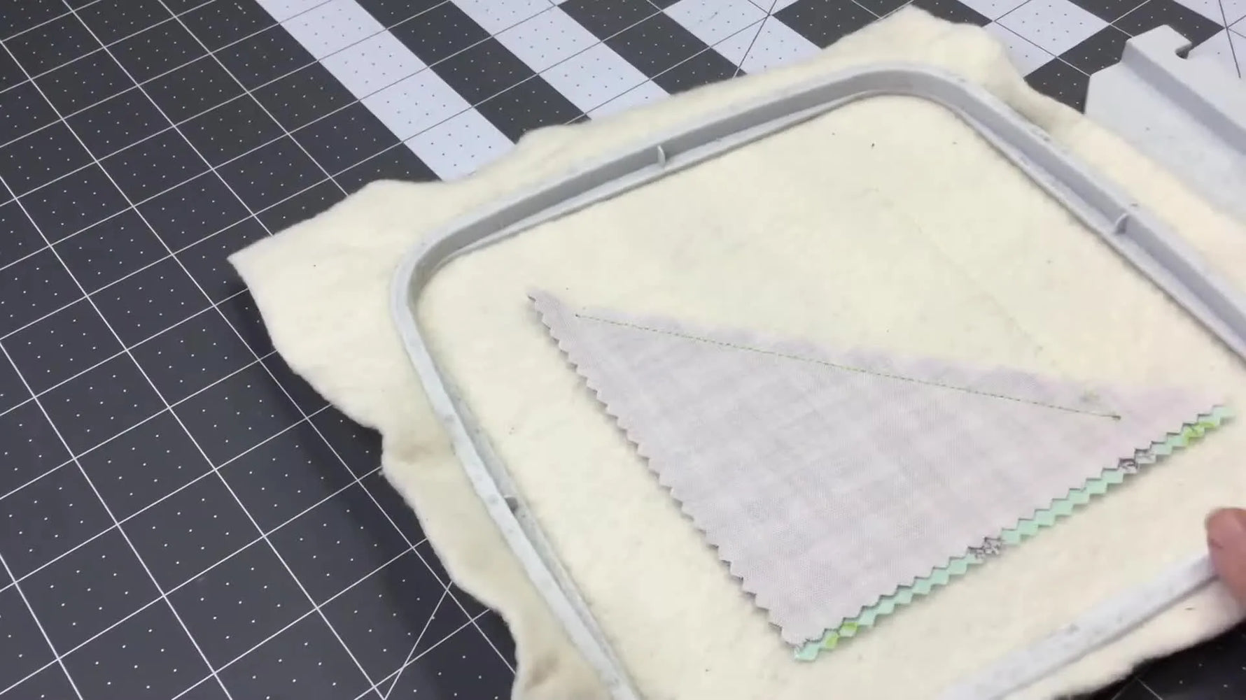 Two contrasting fabric pieces are flipped open in the hoop to reveal a clean, two-tone coaster top ready for decorative quilting stitches.