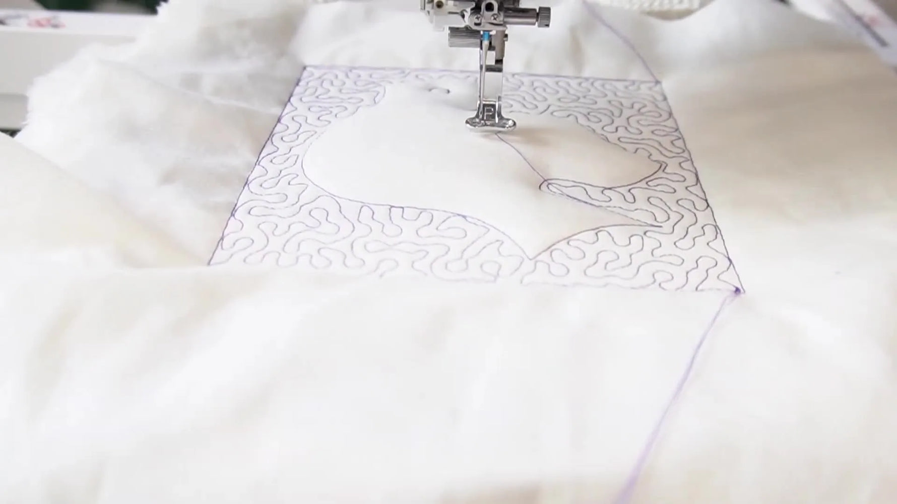 The instructor holds a finished Trapunto dove block with a visibly raised, puffed dove shape and densely quilted background.