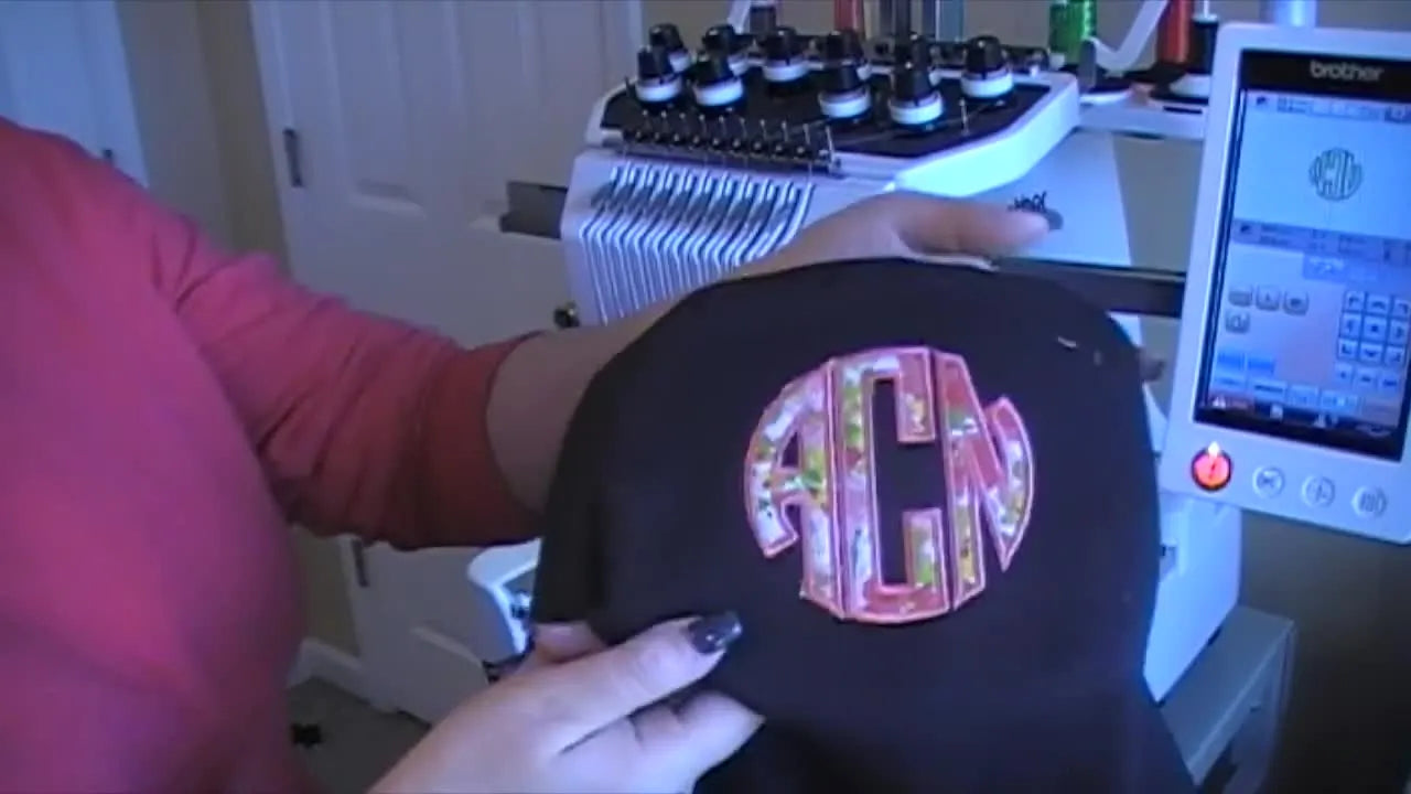 The finished hoodie is held up to show the completed circle appliqué monogram and its left-chest placement.