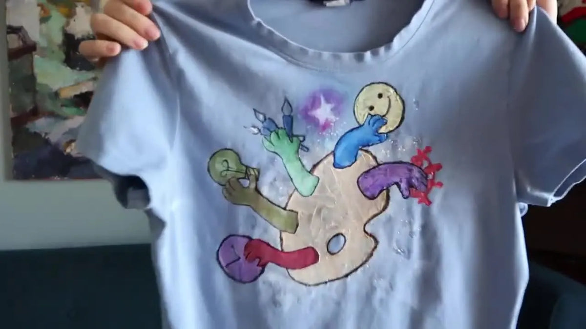 Finished light blue t-shirt decorated with a colorful art palette design.