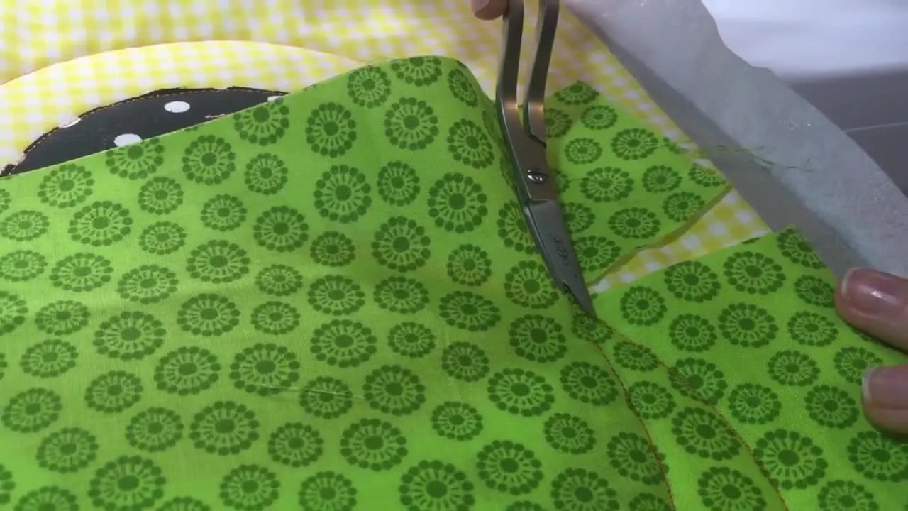 A close-up of the Brother machine stitching a bold satin outline that crisply defines each pumpkin applique segment.
