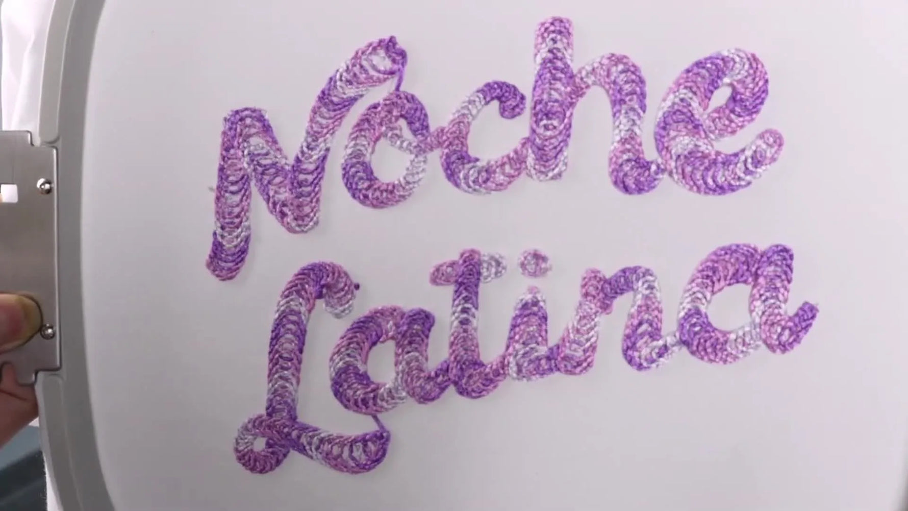 The finished “Noche Latina” yarn-couched embroidery on a white garment, showing the raised chenille-like texture and clean edges.