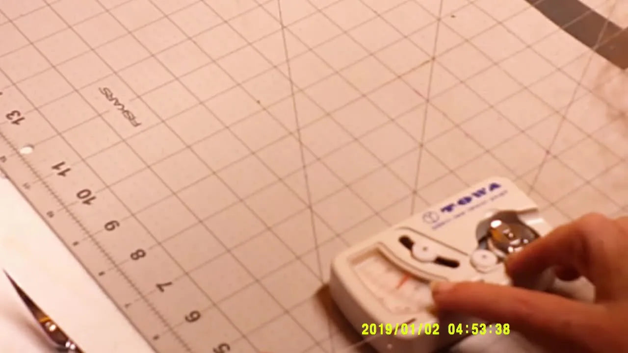 An overhead view of a Towa gauge measuring bobbin tension on a Holiauma bobbin case before running an H-test.