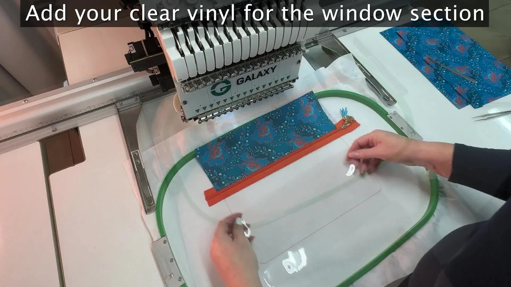 Hands placing a clear vinyl sheet over the window outline on the hooped fabric.