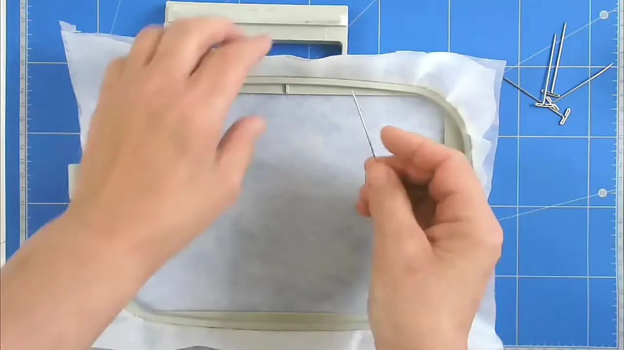 A close-up shows a T-pin sliding over the hoop lip and locking the stabilizer in place for drum-tight tension.