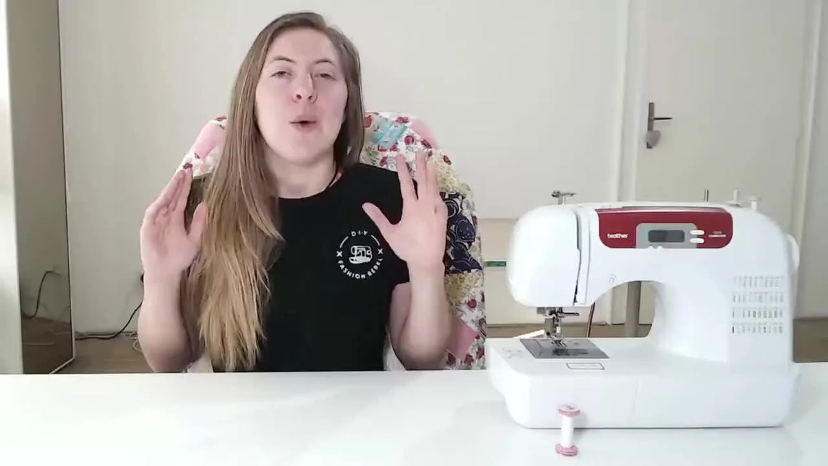 A woman presenting a sewing machine, gesturing with her hands while explaining its features.