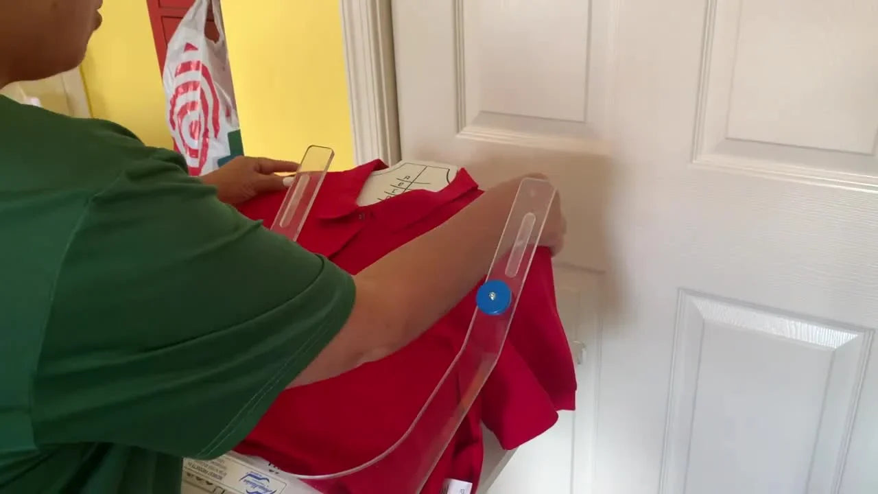 A magnetic top frame snaps into place on a red polo shirt at the hooping station, capturing the exact moment of clean, repeatable hooping.