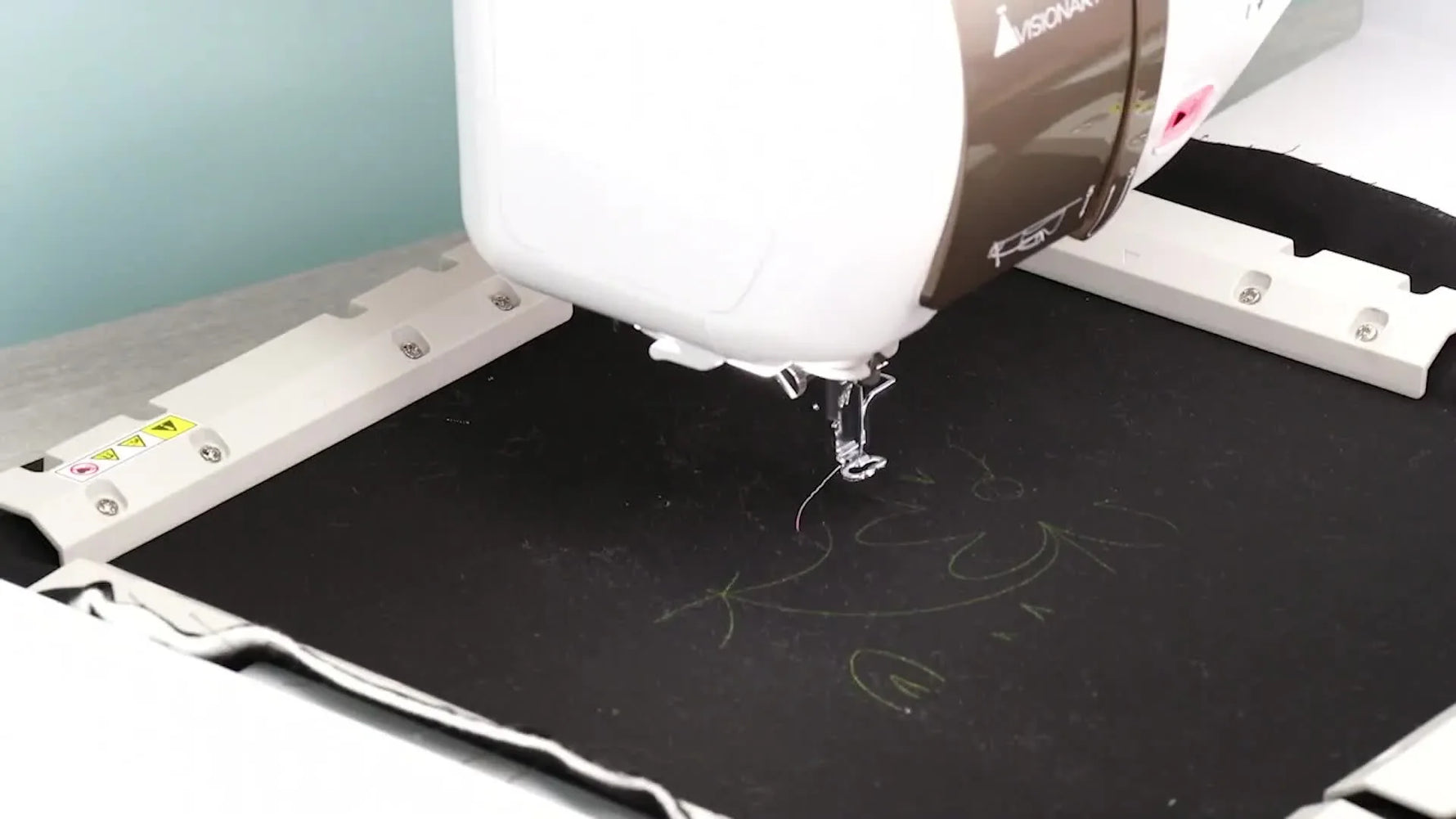 A close-up of the machine projector casting a bright green quilting design onto black fabric for precise placement before stitching.