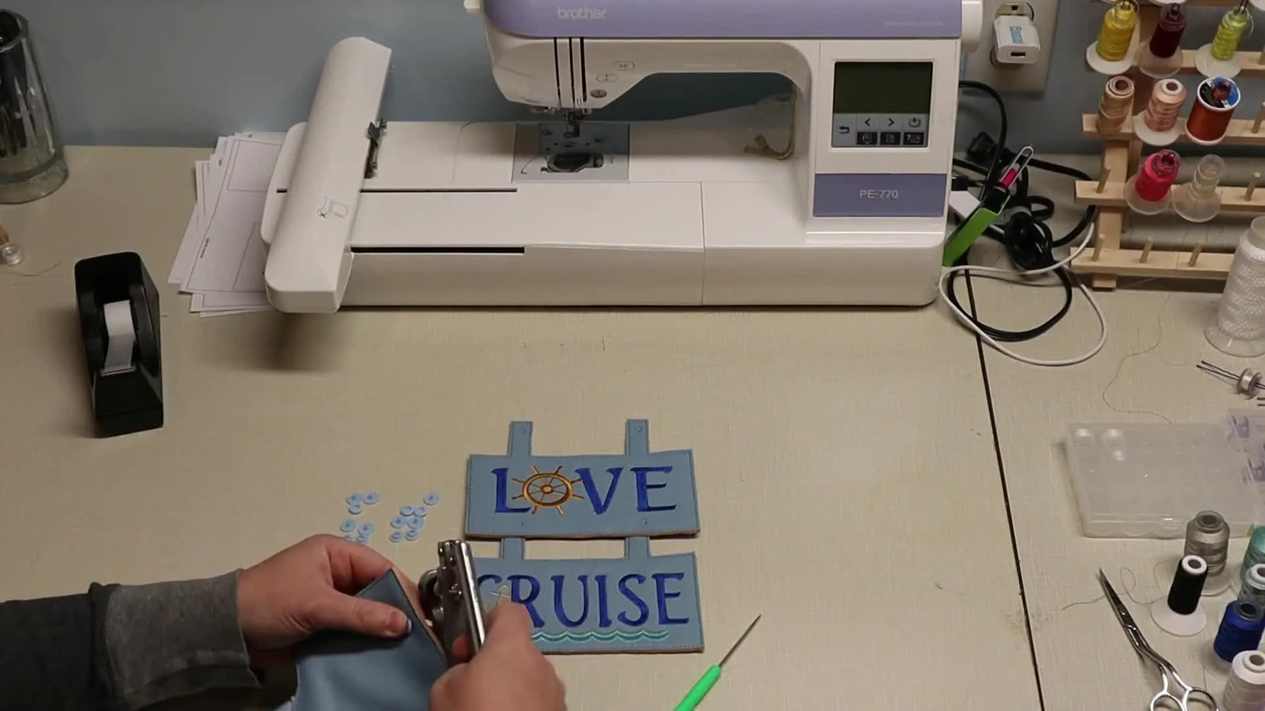 The finished three-panel “Live Love Cruise” in-the-hoop wall hanging is held up for a final reveal.