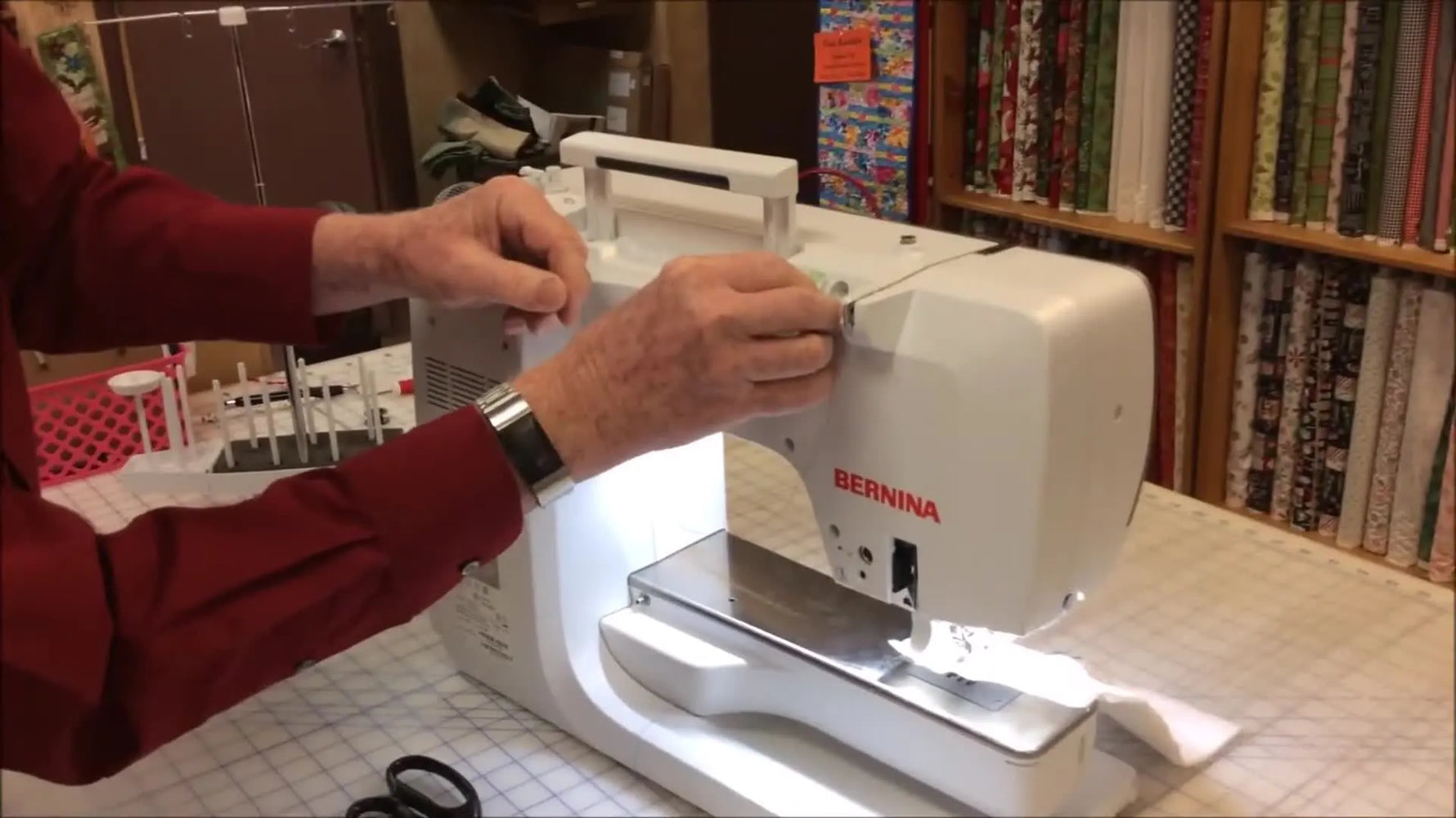 A close-up of the Bernina 7 Series thread path routed through a Wonder Clip mounted high on the machine to prevent slack from dropping out of the upper tension unit.